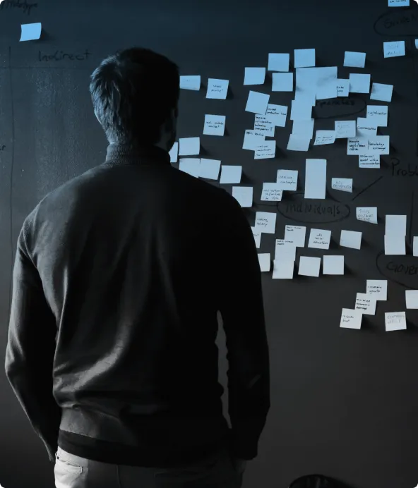 A person standing in front of a wall of handwritten sticky notes, grouped and circled into clusters